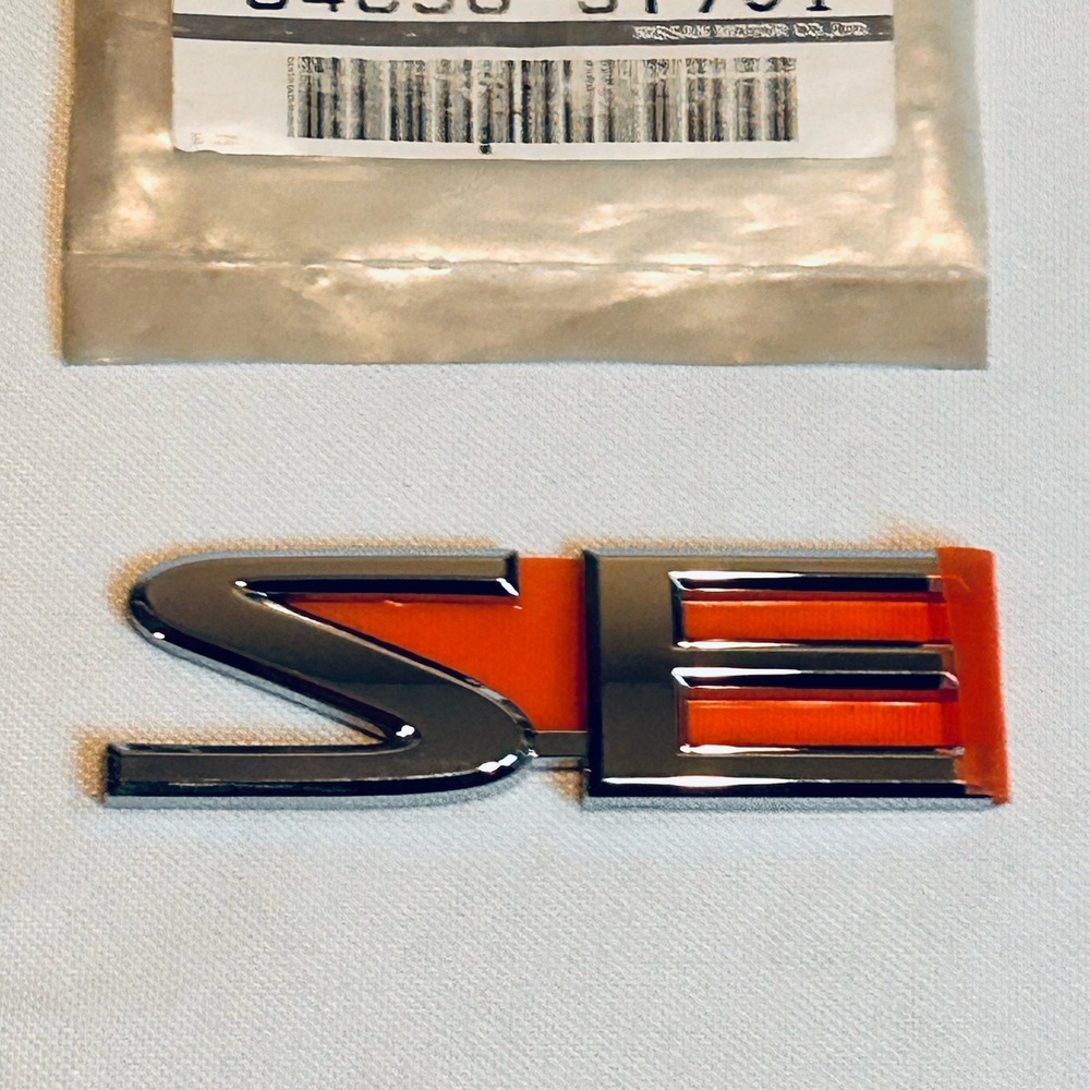 Nissan SE Emblem Badge New 84896-5Y701 Genuine OEM Part 3" Wide Chrome Orange